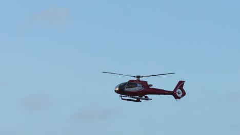 red helicopter flying in clear blue sky