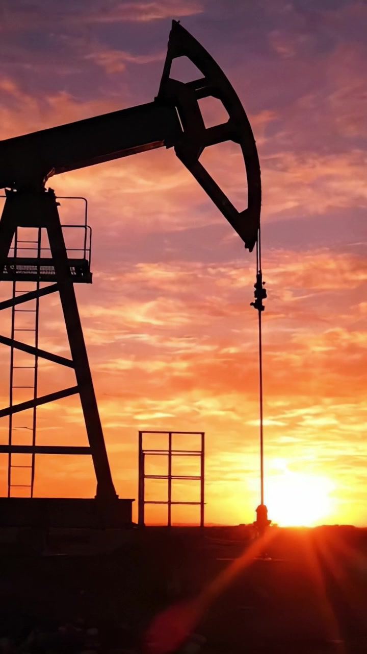 Silhouetted Oil Pump Jack Against a Stunning Sunset: A Visual Representation of the Oil Industry's Impact on Natural Landscapes