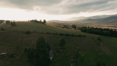 Aerial-racing-drone-following-an-unpaved-road-in-a-beautifully-sunlit-nature-scenery-with-trees-casting-long-shadows