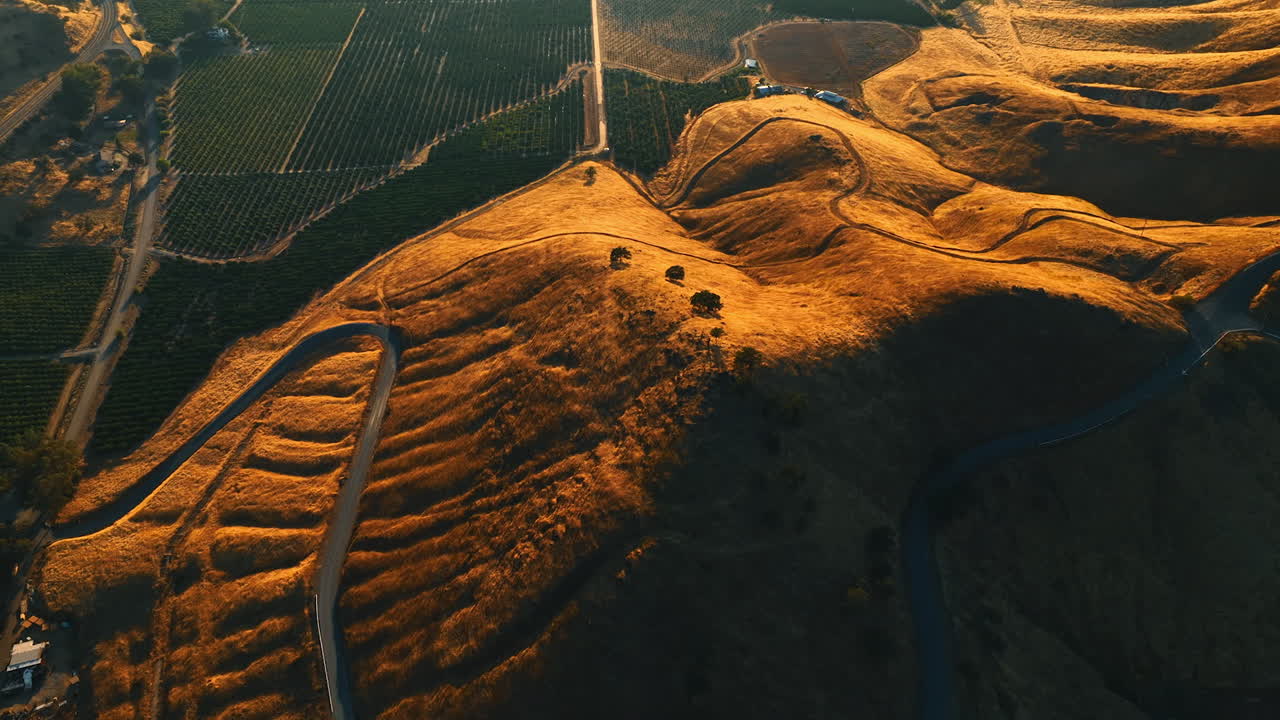 Splendid view of the rolled bare rocks neighboring with green vineyards in California. Highway passes by the surface of mountain. Top view.