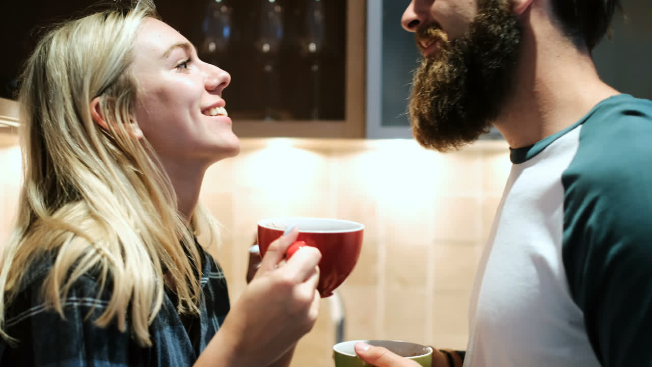 pareja besándose mientras toman café en la cocina 4k