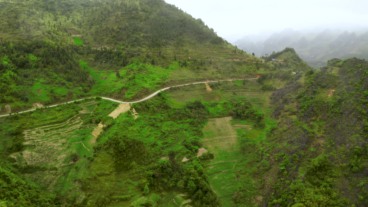 carretilla aérea hacia adelante mientras se inclina hacia arriba para revelar un camino panorámico cortado en las montañas del hermoso paso ma pi leng en el norte de vietnam