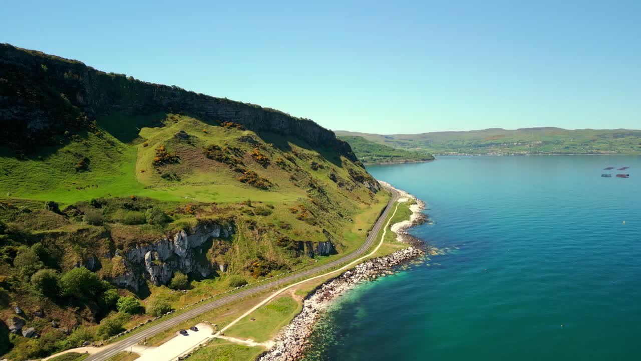 Side-on aerial video of the Causeway Coastal Route on the coast of County Antrim, Northern Ireland, UK, on a bright and sunny day. Filmed in 4K, 60FPS and with Rec709 color.