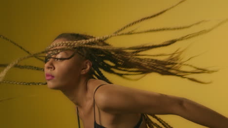 African-woman-performing-modern-dance-and-shaking-dreadlocks-in-dance-studio