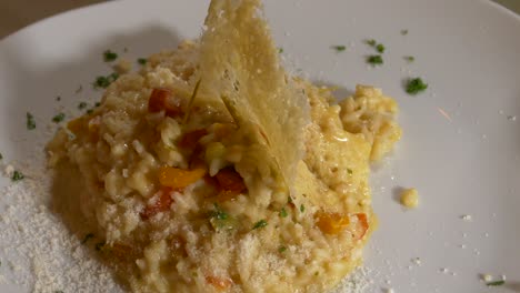 risotto de pimientos bellamente emplatado con un waffle de parmesano filmado en una lazy susan
