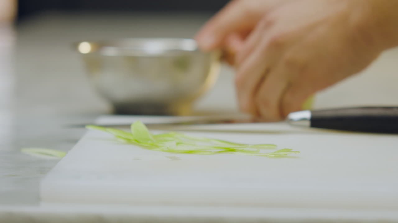 Uno chef sbuccia e taglia una mela verde su un tagliere posto su un bancone bianco