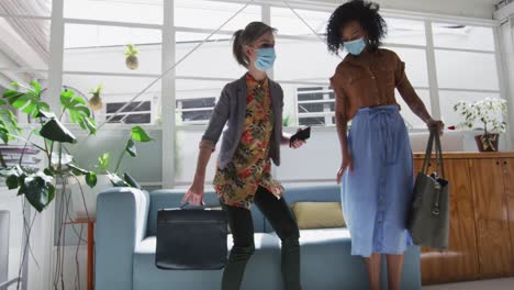 two woman wearing face masks sitting on a couch at office