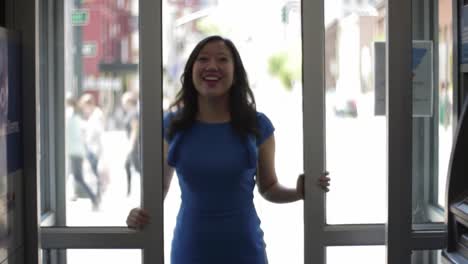 a woman in a blue dress stands at an entrance, poised to step outside into a bustling street, hinting at a story unfolding in an urban environment full of life.
