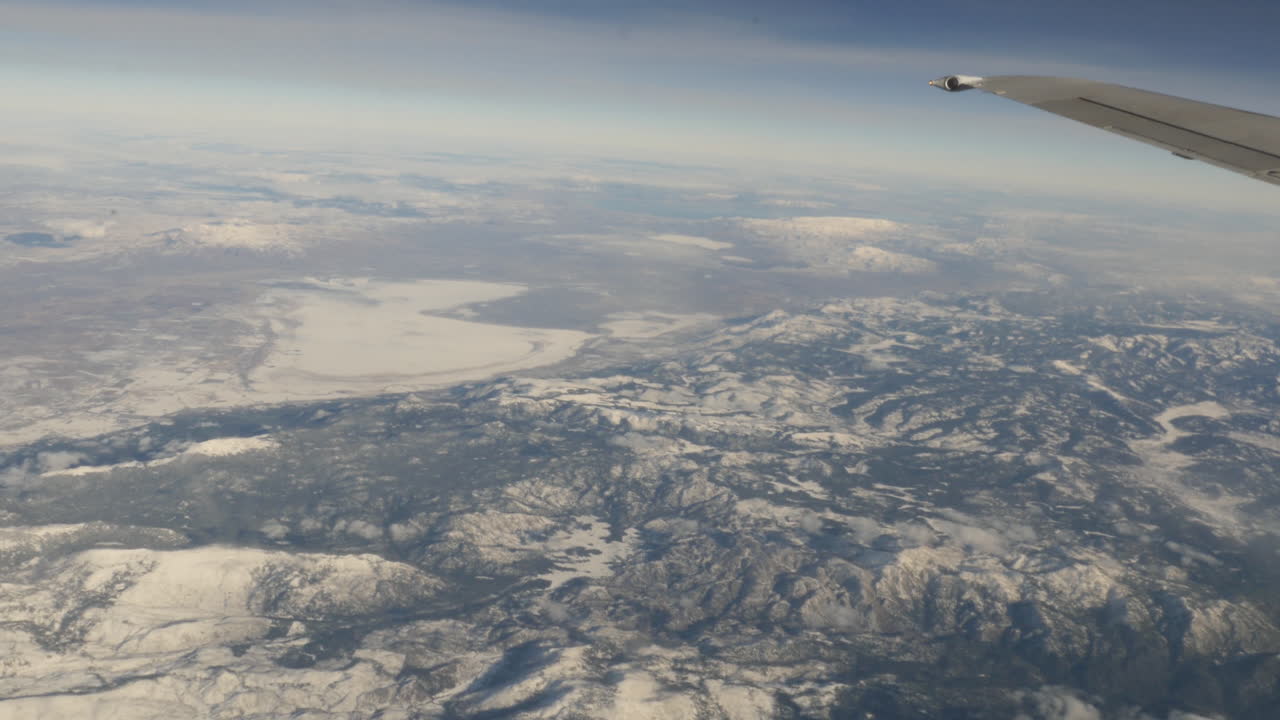 vista aérea de montañas cubiertas de nieve desde la ventana de un avión volador filmada en alta resolución de 4k