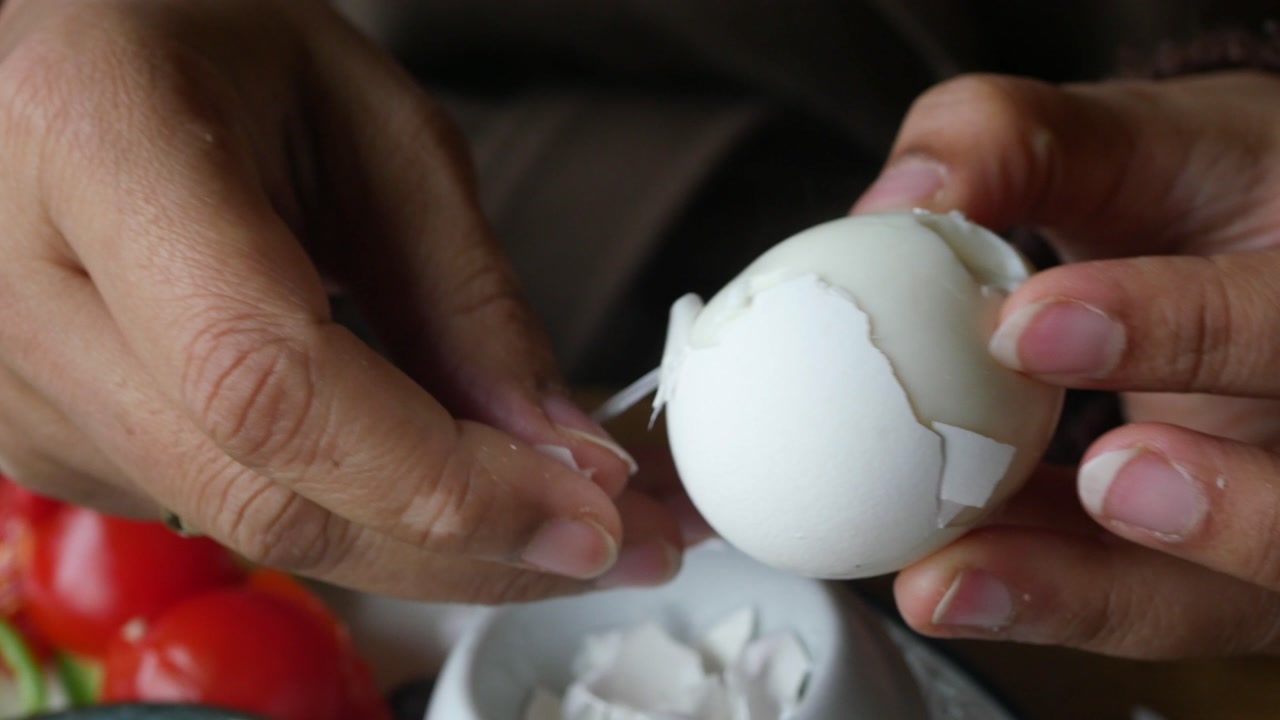 Hands Carefully Peeling a White Boiled Egg
