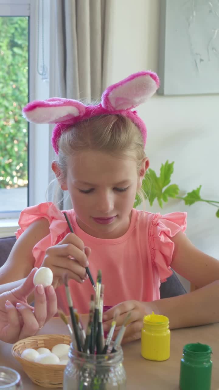 Ragazza che prende i colori, accetta un uovo da una mano d'aiuto, intinge i pennelli e dipinge per un lavoretto artigianale.