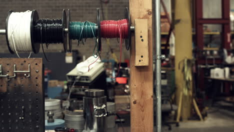 sliding shot of wire spools on a worker's tool bench