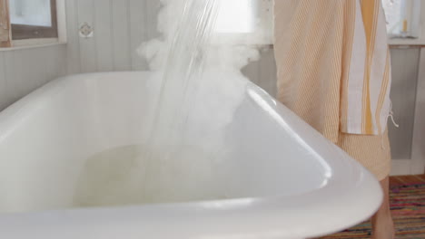 Boiling hot water being poured into steaming old bath in slow motion