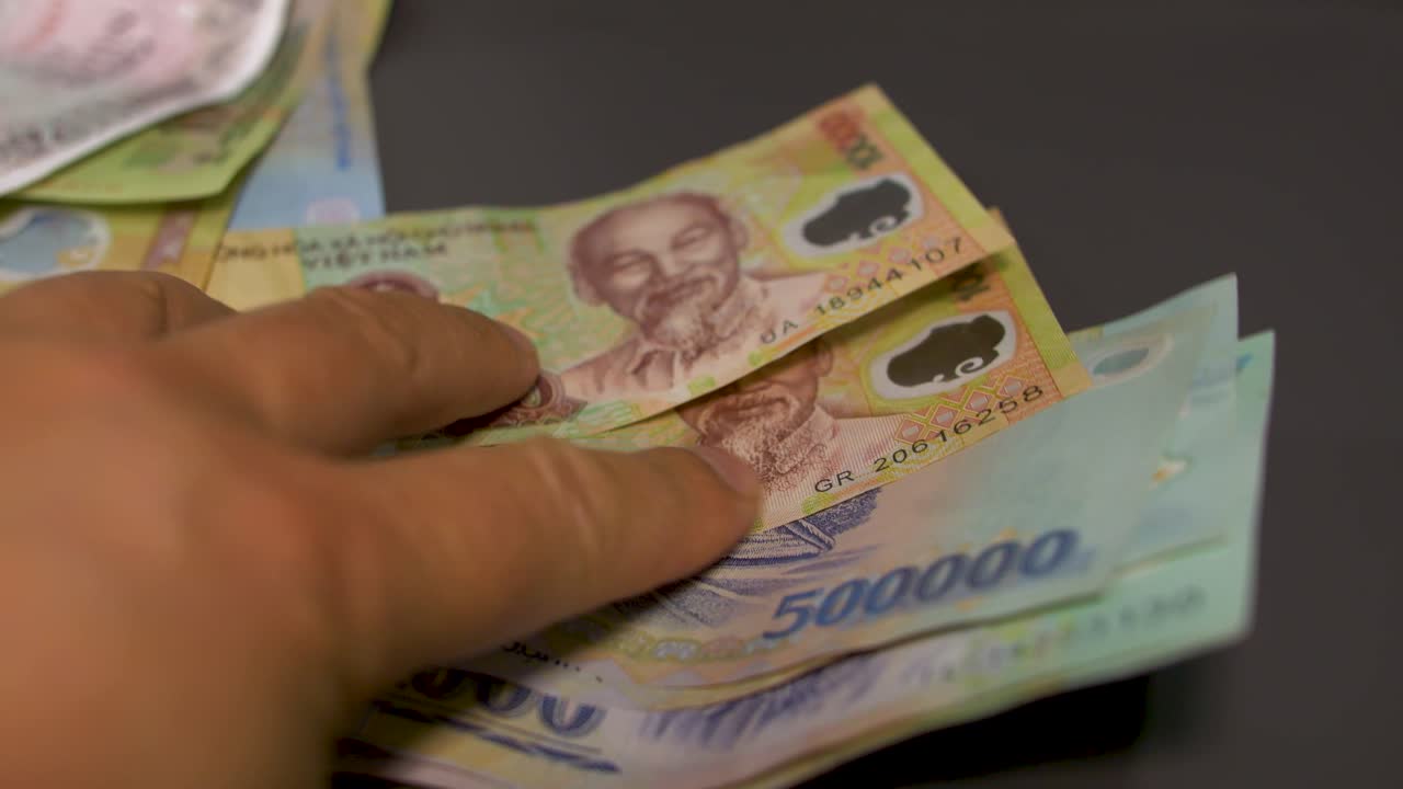 person flipping through different vietnamese dong cash bills