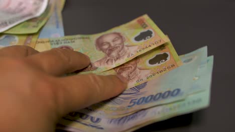person flipping through different vietnamese dong cash bills