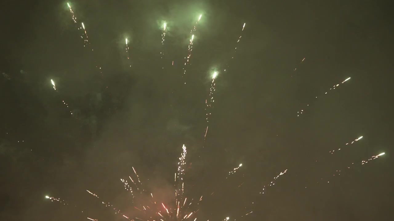 Céu noturno com espetáculo de fogos de artifício, apresentando explosões de luz e rastros de fumaça.