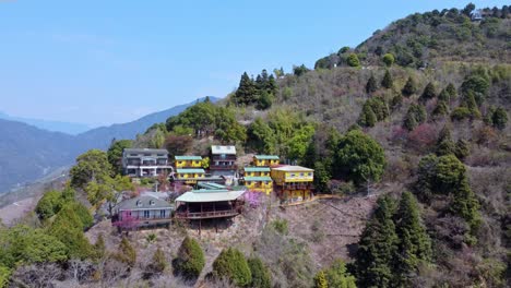 colorful buildings nestled on a green hillside, under a clear sky, aerial view