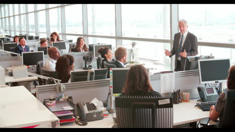 colleagues talking at a desk in a busy open plan office