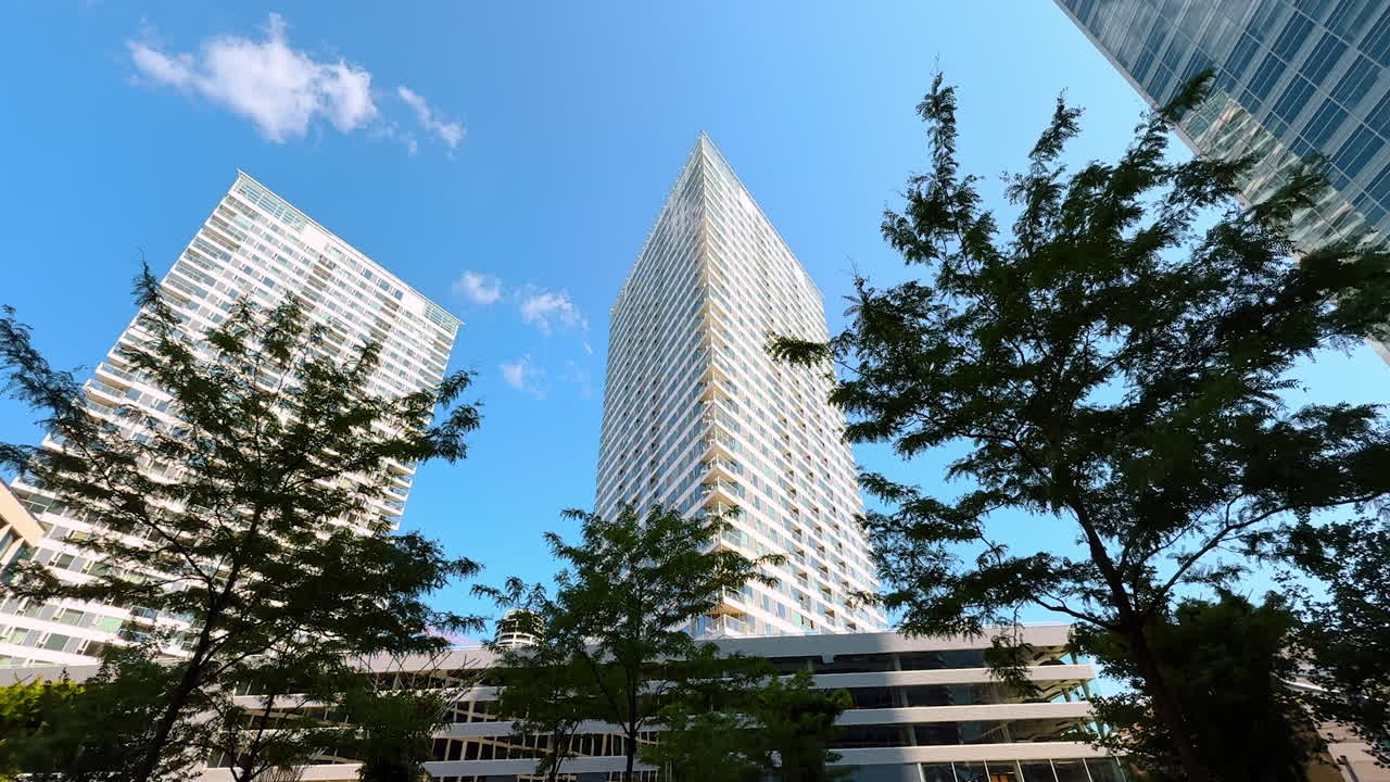 Modern skyscrapers in an urban landscape. Two towering skyscrapers rise against a bright blue sky, surrounded by greenery in a contemporary city environment