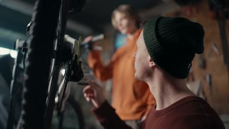 dad and son work in the garage: dad teaches son how to fix a bike. dad spins the wheel to see if the bike is working