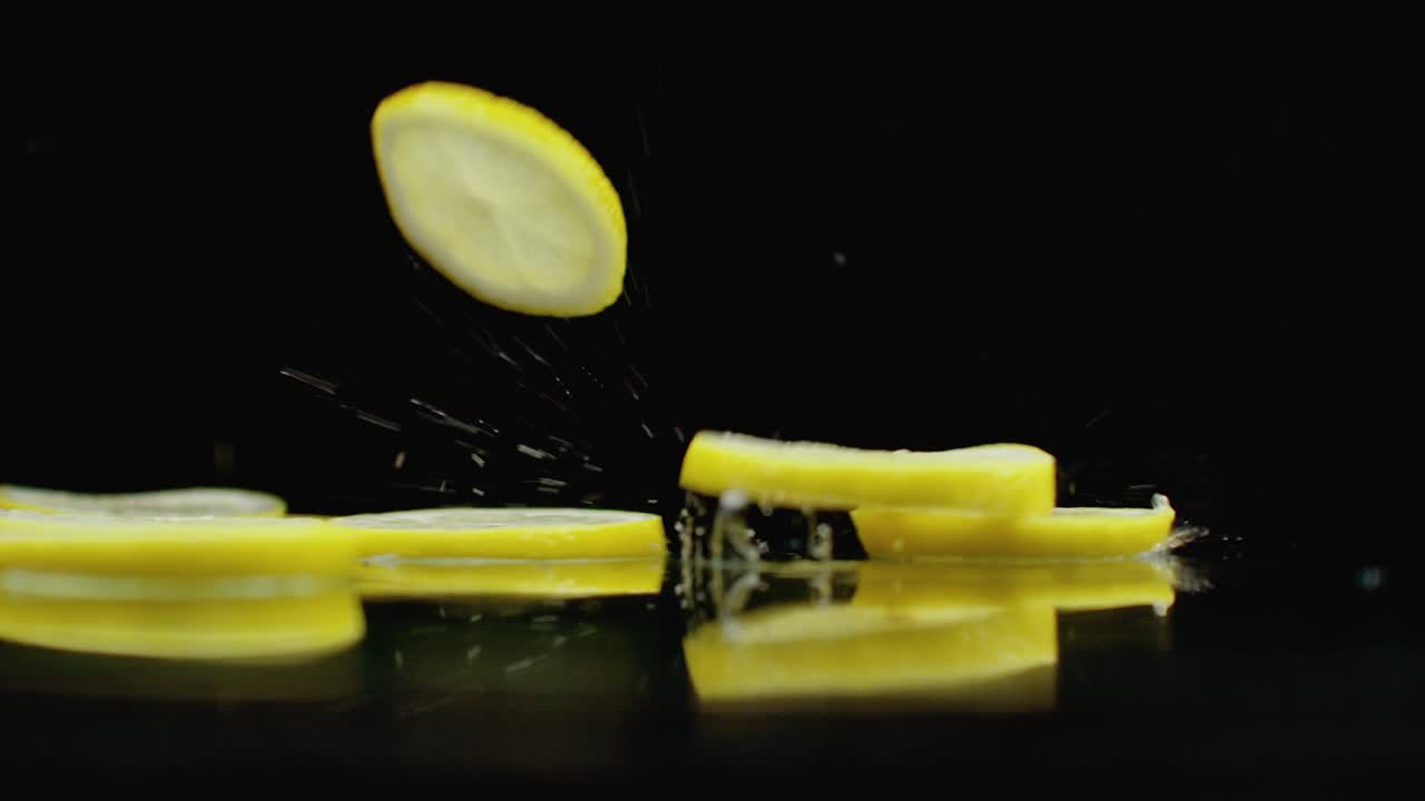 매운 프레트 조각은 반사와 스프레이와 함께 테이블에 떨어집니다. 노란색 익은 레몬의 반지의 느린 움직임