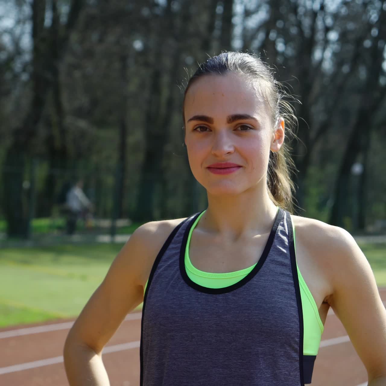 Fit and beautiful. Beautiful young woman in sports clothing smiling and looking a camera while standing outdoors