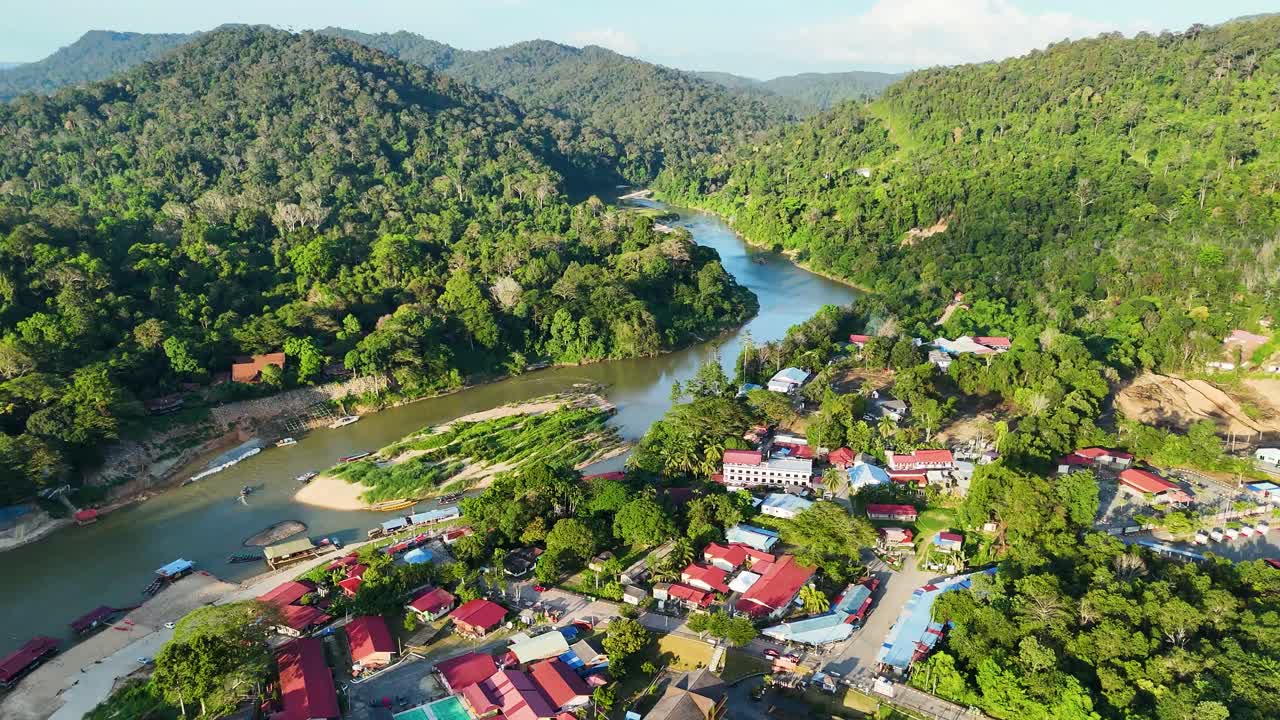Aerial: Kuala Tahan, Malaysian village with Tembeling River in Taman Negara National Park during the day in Peninsular Malaysia, pull out drone shot