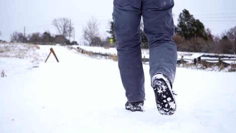 Vista-De-ángulo-Bajo-Del-Hombre-Caminando-En-Un-Sendero-Cubierto-De-Nieve-En-Cámara-Lenta