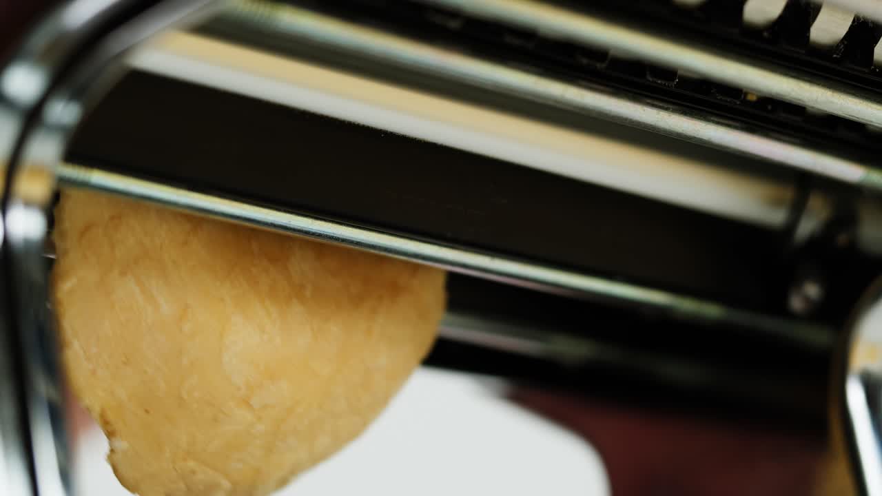 Close-up of Pasta Dough Being Rolled Through a Pasta Maker