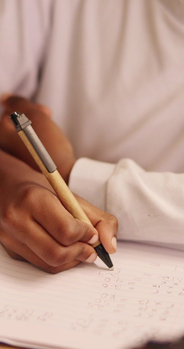 Student Writing Math Equations on Paper