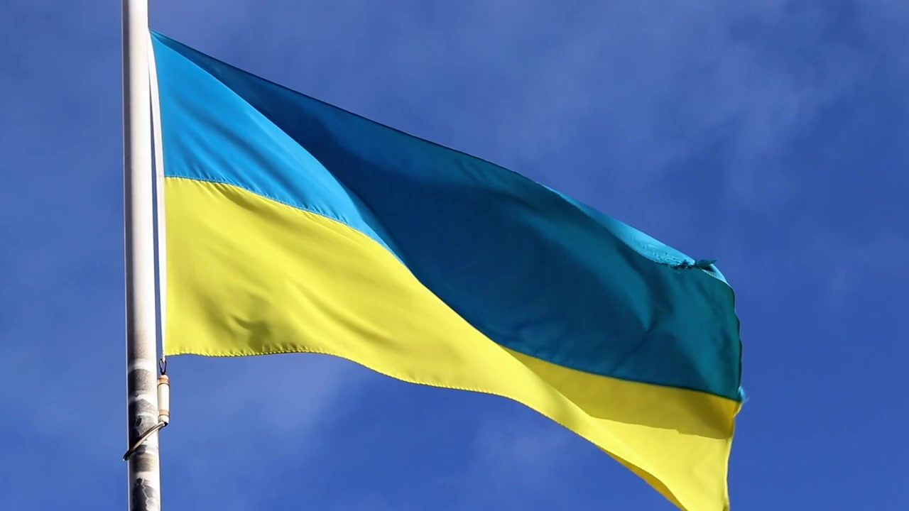 Bandiera ucraina che sventola lentamente al vento nel cielo blu.