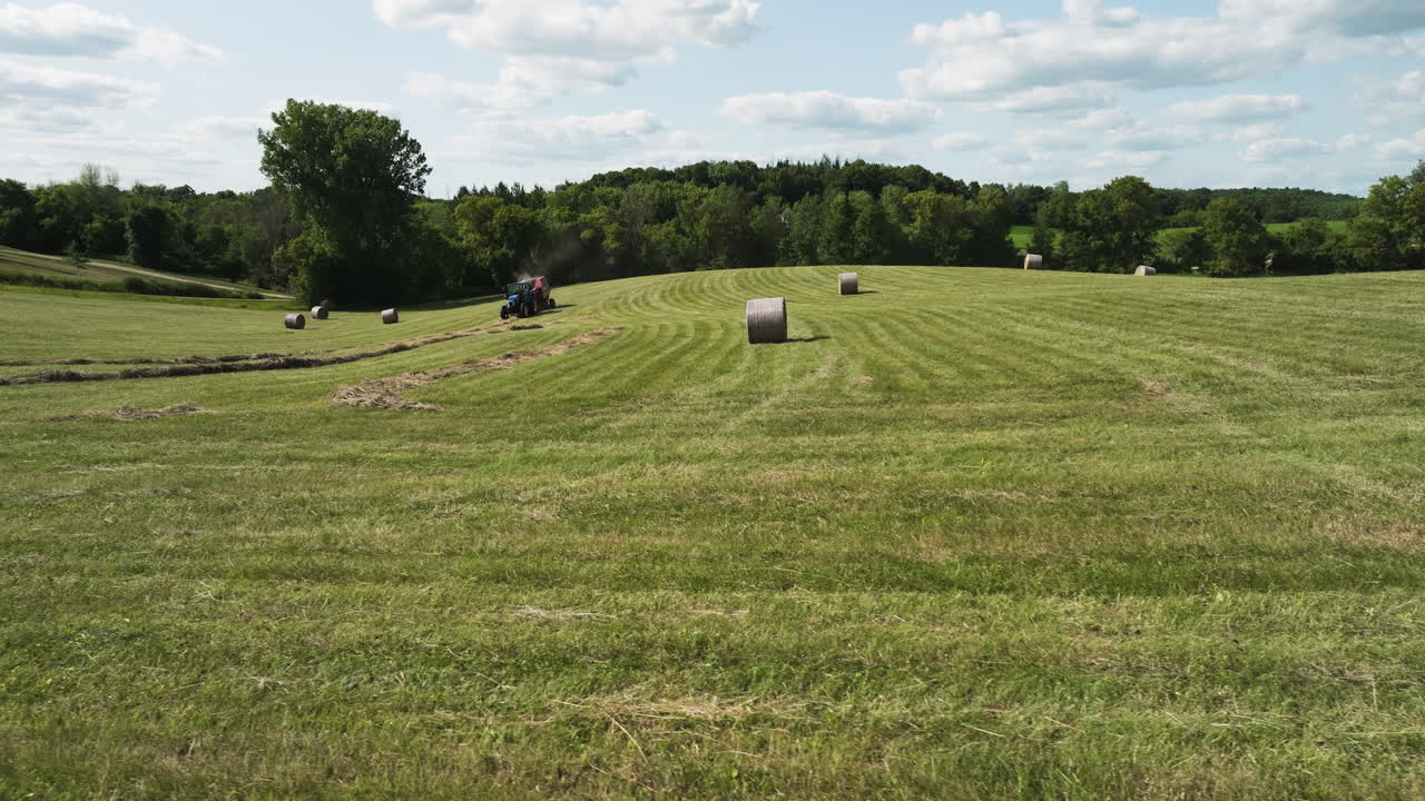 Toma panorámica de la vida idílica de un agricultor recogiendo heno en su tractor