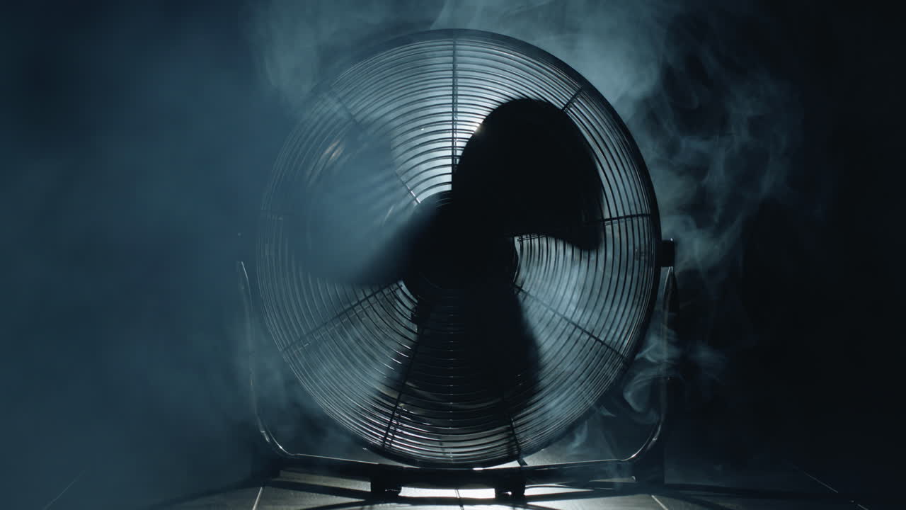 팬 블레이드는 빛과 안개의 광선에서 회전합니다.