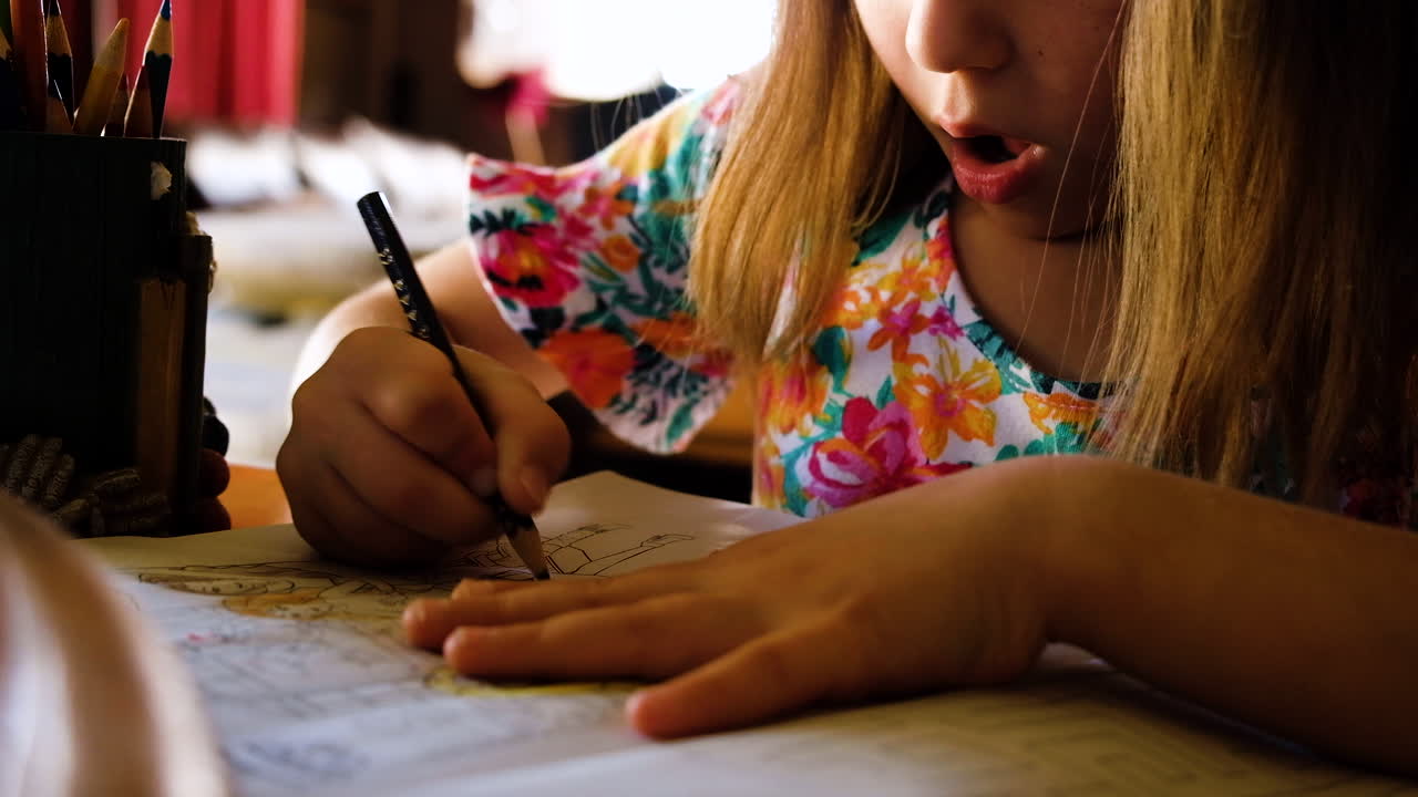 Young caucasian girl moves tongue in concentration as she's coloring in