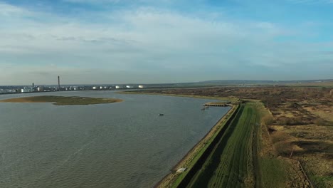 Aerial-:-Descending-drone-shot-above-pier-with-industry-and-tankers-in-distance