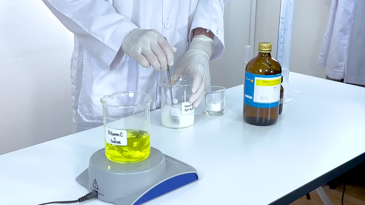 A scientist performs an iodine clock reaction using vitamin C and starch, demonstrating chemical change in a laboratory setting