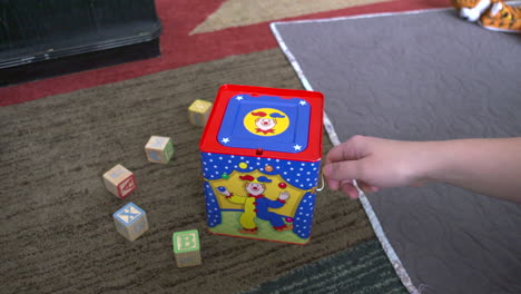 A-woman's-hand-winding-a-jack-in-the-box-toy-until-it-pops-up