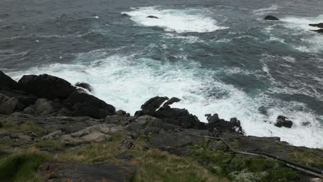 Video-Fijo-Del-Agua-Golpeando-Las-Rocas-Debajo-Del-Faro-De-Kråkenes-En-Noruega,-Video-Mirando-Hacia-La-Orilla