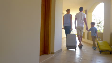 family of three with roll-on bags in hotel