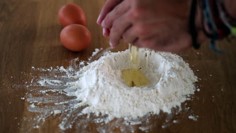 making pasta dough with eggs and flour on board