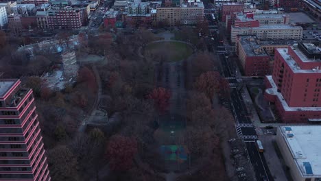 Fast-drone-flyover-rooftops,-highrise-and-urban-park-in-Harlem,-New-York-City