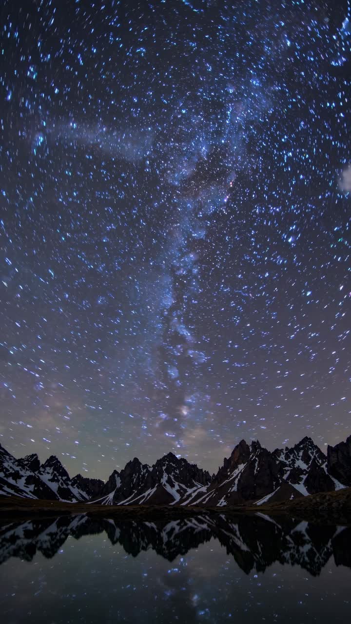 A mesmerizing time-lapse video of a starry night sky over jagged mountains, captured from a low