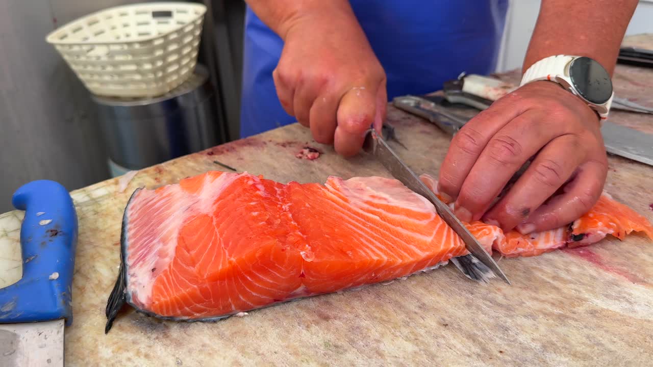 Close-up of Hands Filleting Fresh Salmon on a Cutting Board