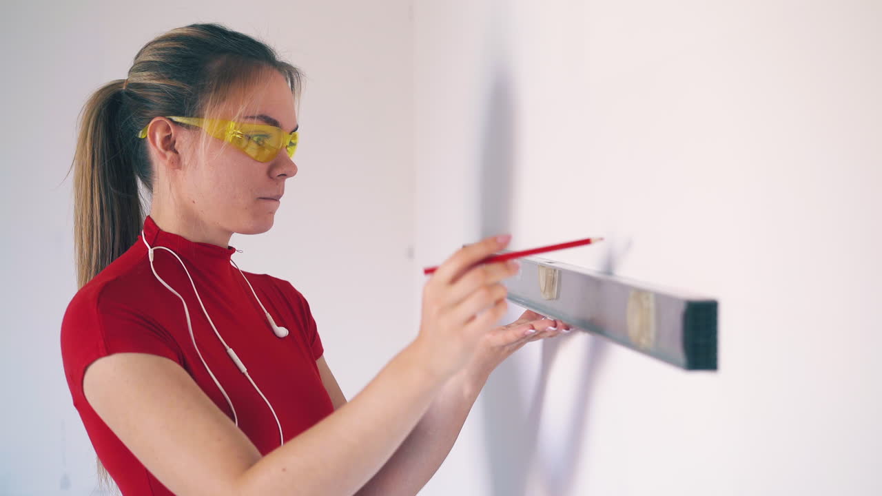 una bella donna controlla il livello della parete usando uno strumento nella stanza