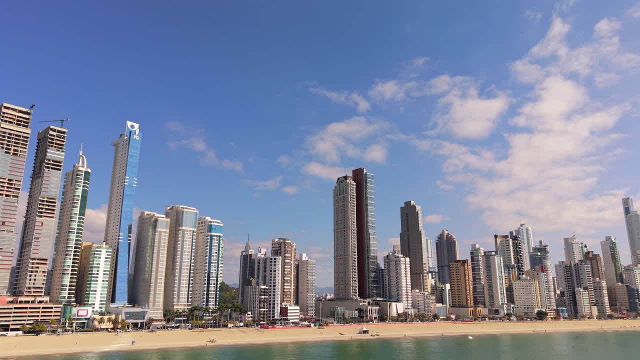 Beachfront skyline of Balneário Camboriu, Santa Catarina, Brazil, with iconic towers as Yachthouse Residence Club, One Tower, Infinity Coast, Epic Tower rising above Avenida Atlântica, drone orbiting
