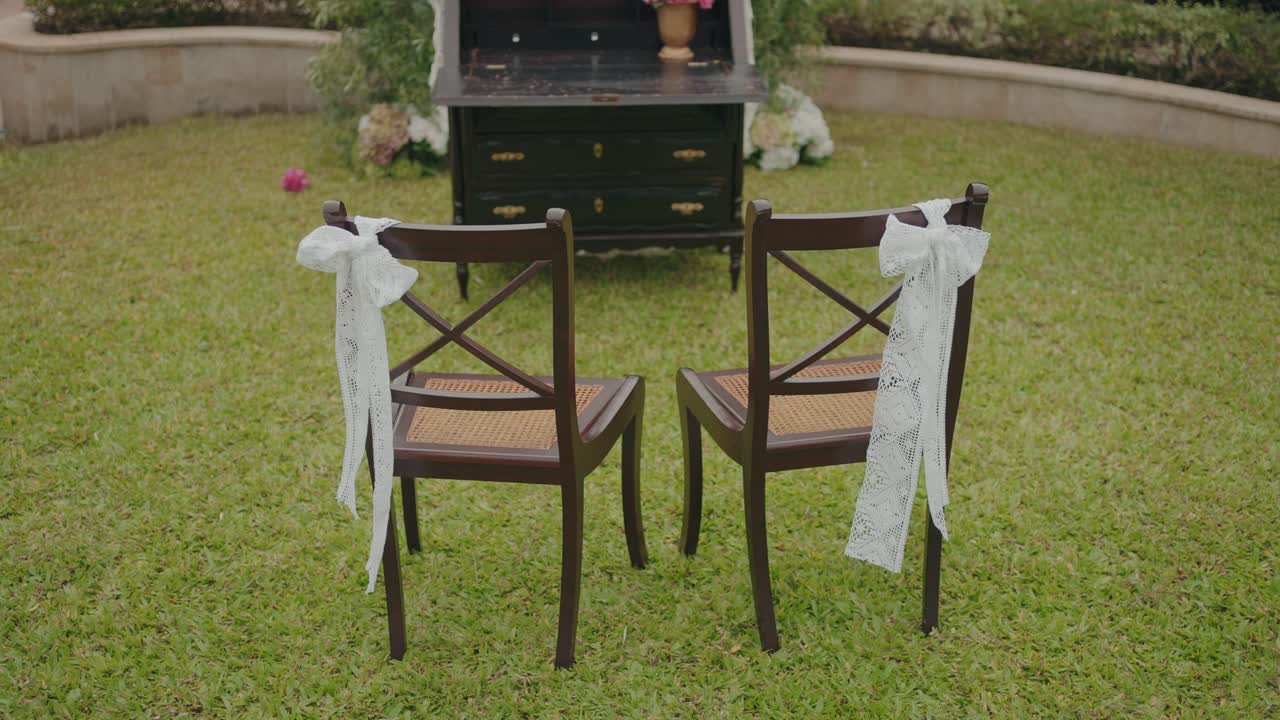 Due sedie di legno con nastri di pizzo posizionati sull'erba per l'allestimento di un matrimonio