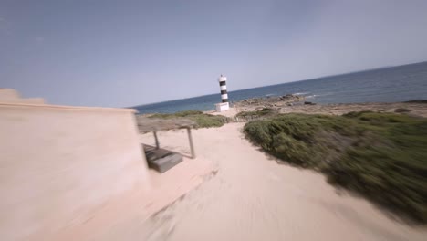 FPV-drone-shot-of-Punta-Plana-lighthouse-over-rocky-beaches-in-Faro-de-s'Estalella,-Mallorca,-Balearic-Islands,-Spain-at-daytime