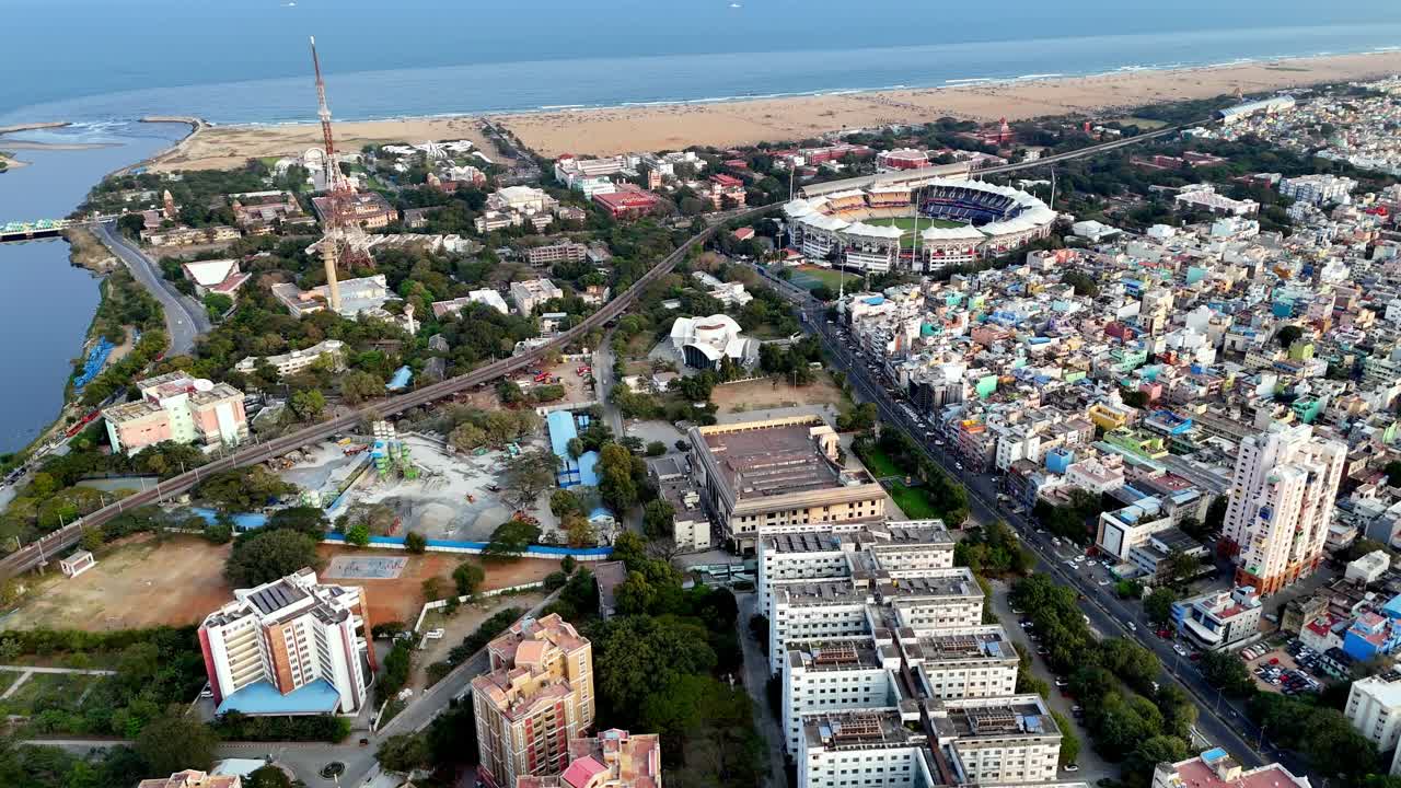 Veduta aerea dello stadio Chepauk a Chennai, che mostra l'iconico campo da cricket circondato dai quartieri della città con Marina Beach e la Baia del Bengala che si estendono lungo la costa sullo sfondo