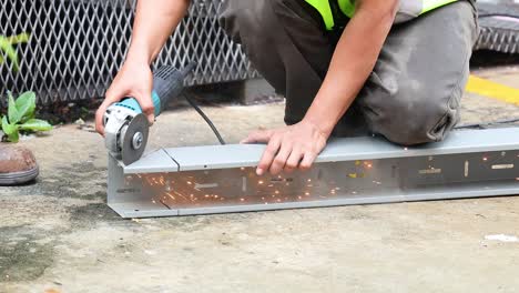 worker using grinder to cut metal piece