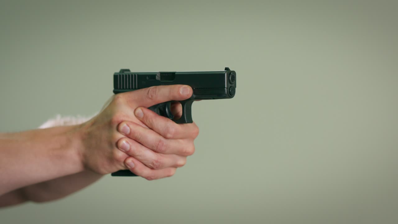 실내 훈련장에서 목표물을 겨냥하고 총을 는 사격 강사의 손의 클로즈업